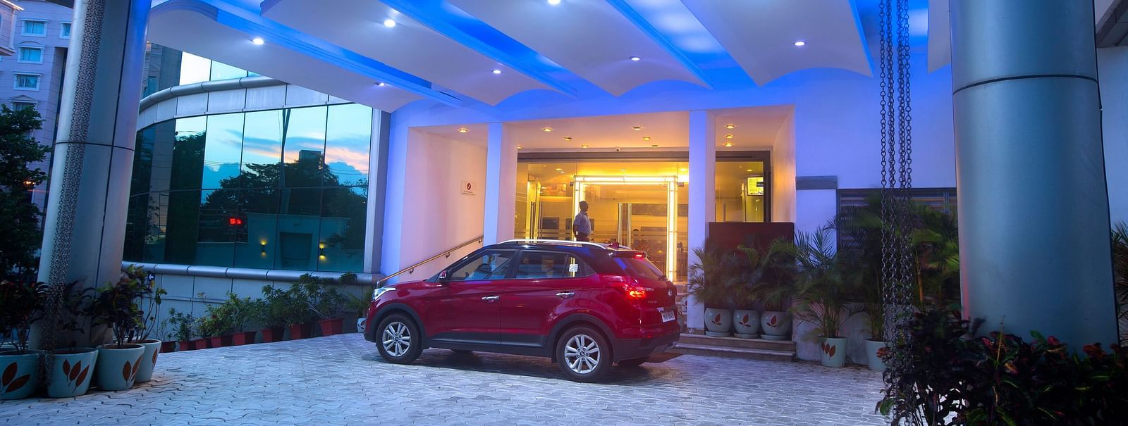 a red car parked at the entrance of Hotel Atithi - TGI Grand, Pondicherry