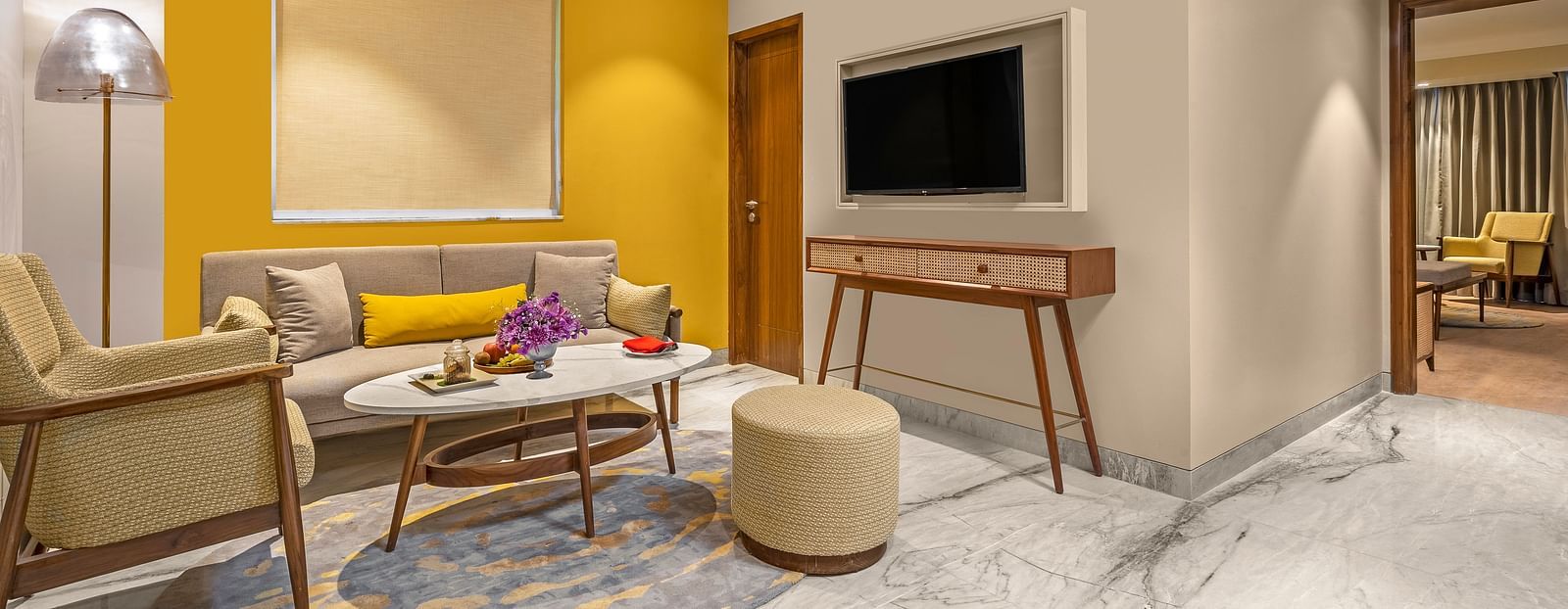 An image of a living room featuring a comfortable sofa, a coffee table, a television mounted on the wall.
