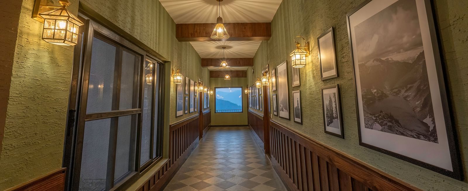 An elegantly styled hotel corridor at The Chamomile Estate, adorned with wall paintings and bathed in warm lighting.