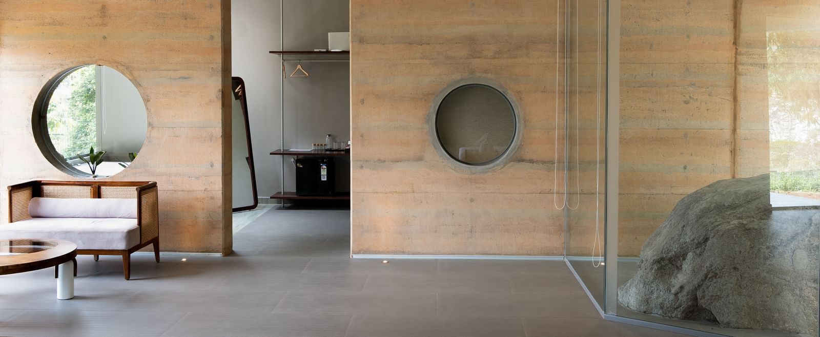 A contemporary interior space featuring wooden walls, a circular window, and modern furniture | Gaia Studio | RD's Nature Retreat, Bangalore