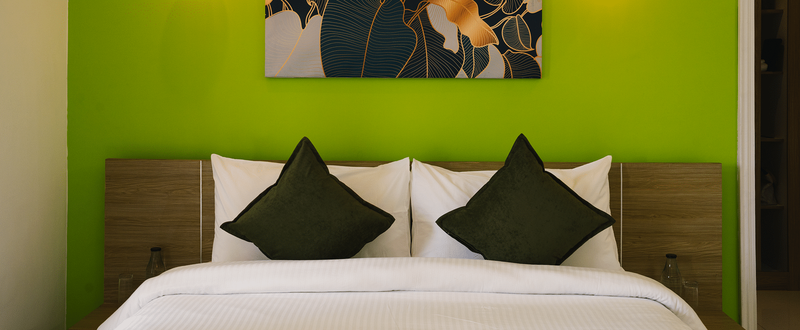 A close-up view of the neatly made bed with a photo frame above the headboard and two light lamps on either side at BluSalzz Villas - The Green Roof, Bhimtal.