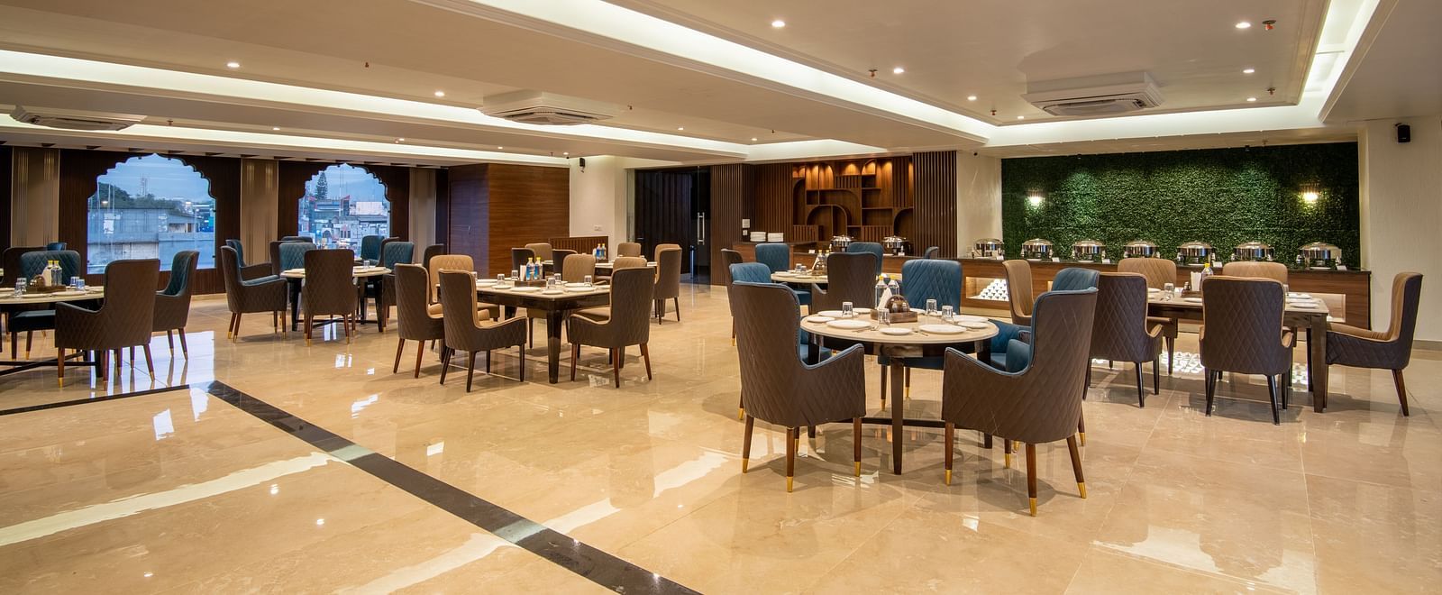 A shot of Ruttba, one of the best restaurants in Dehradun featuring chairs and tables with warm interior lighting - DLS Grand Luxotica