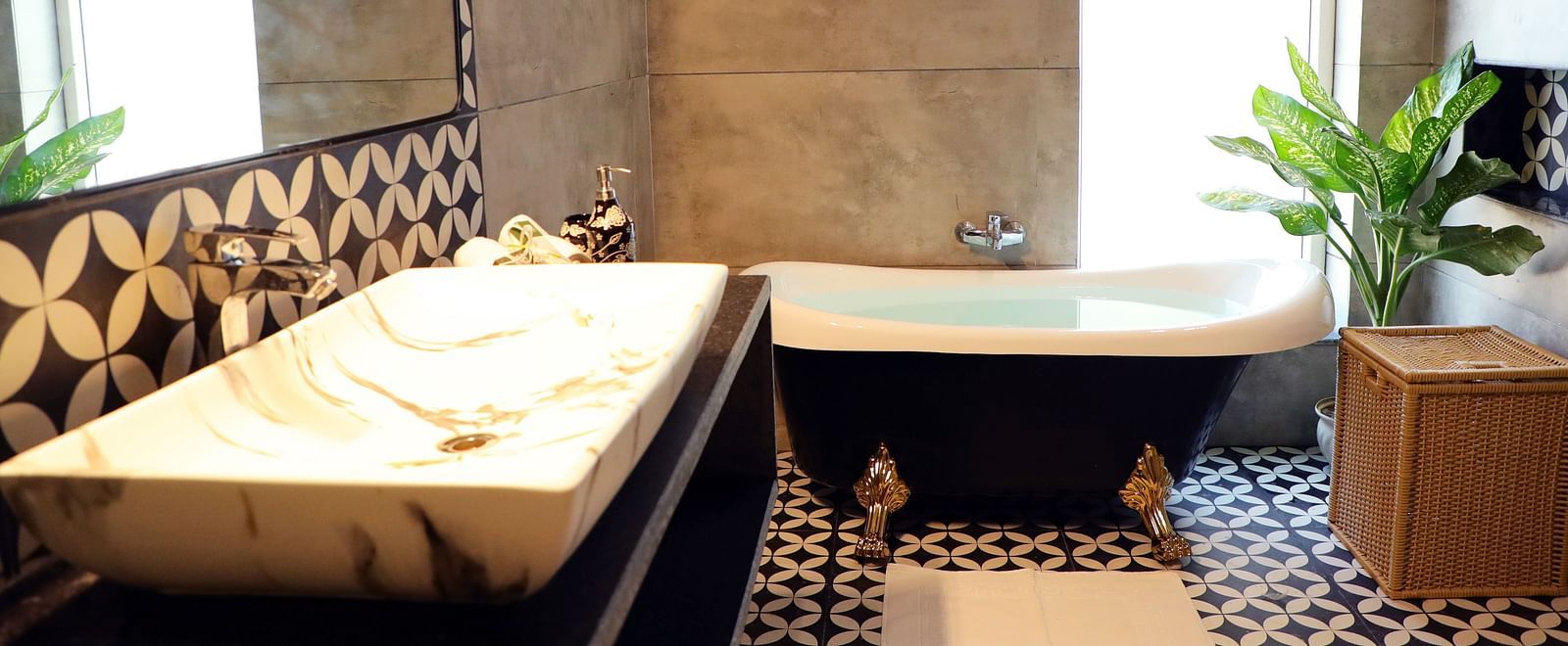 A modern bathroom featuring a sleek wash basin and a luxurious bathtub at Tisya Farms, Gurgaon.
