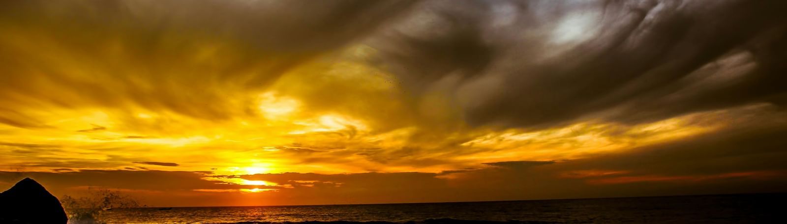 Dramatic sunset over the rocky coastline with vibrant orange and yellow hues