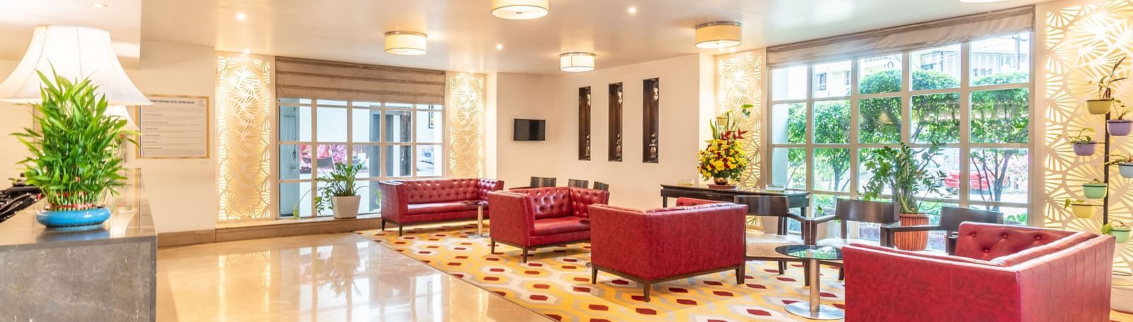 Elegant hotel lobby with modern furniture, red armchairs, and large window- TGI Grand Fortuna, Krishnagiri Main Road, Hosur