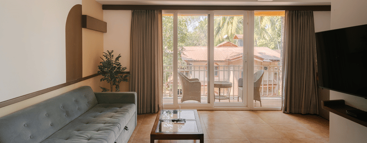 Well-lit living room with a cozy seating area and a balcony at the Two BHK apartment in Richmonde Ananta Elite, Goa.