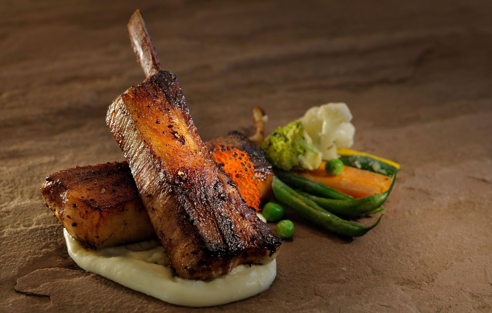 Roasted pork rib and belly with vegetables on stone.