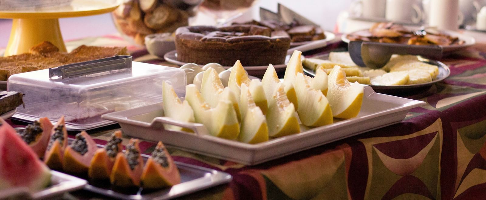 Buffet setup with assorted cut fruits, and covered serving dishes arranged neatly on a table at Fireflies Resorts, Kabini.