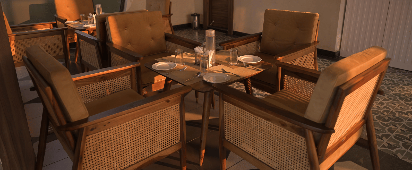 Cosy indoor lounge with wooden chairs arranged around a central table at Hotel Sonar Bangla Mayapur.