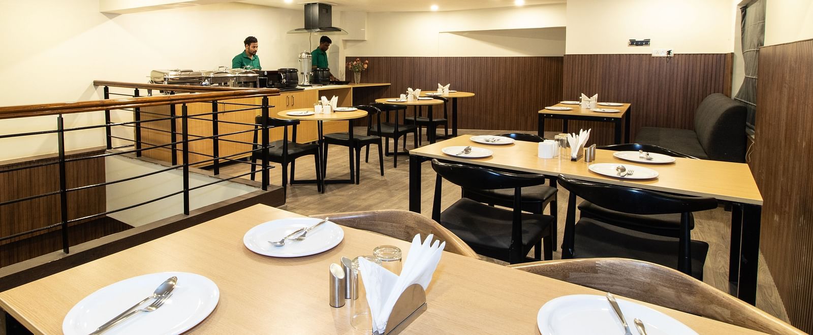 A dining area with wooden tables and chairs in a warm inviting setting - Sanctum Suites Richmond Road, Bangalore