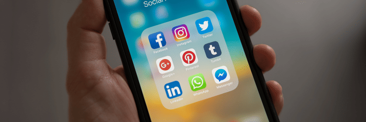 A close up shot of a person holding a phone showing social media apps.