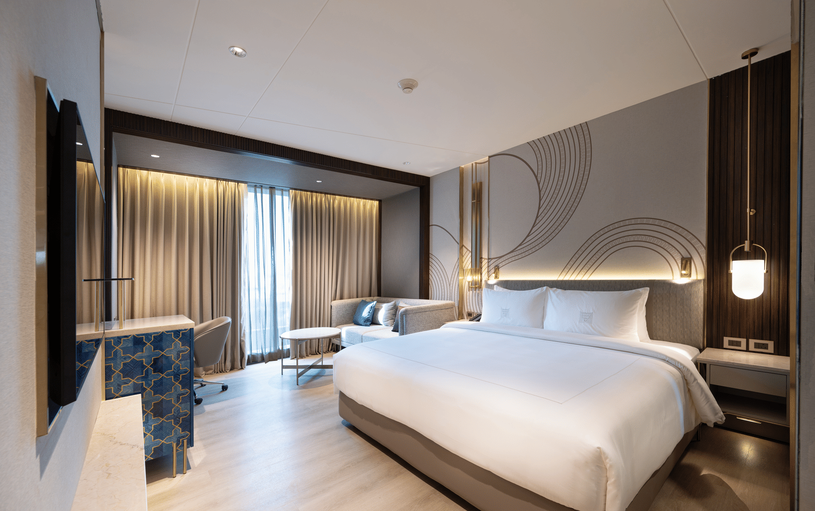 A bedroom featuring a plush bed facing the TV on the wall and a large ceiling-to-floor window covered with curtains at Merlis Hotel, Coimbatore