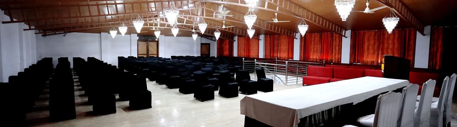 Image of a banquet hall with chairs and a pulpit in front at Amara Hill Queen, Mussoorie.
