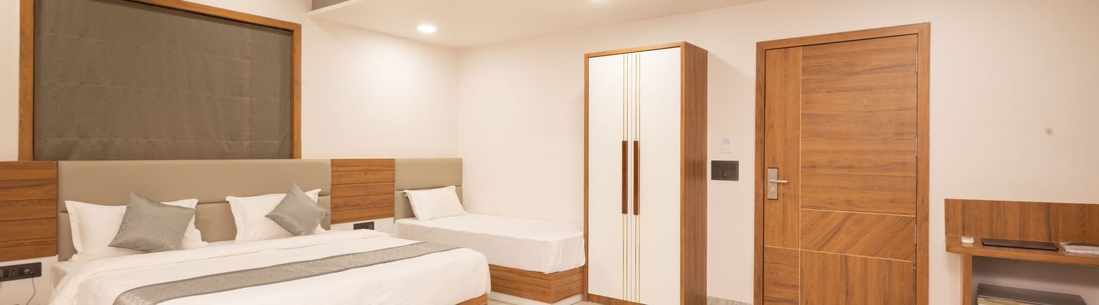 Wide view of the Daksh Pride room at Daksh Eden Greenz, Sasan Gir, showcasing its double, and single bed, wardrobe, and spacious layout.