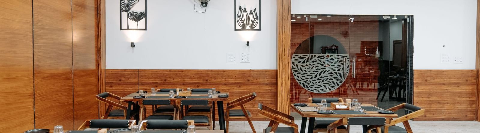 A shot of some tables at the restaurant of the resort that has wooden furnishing and wall mounted paintings.