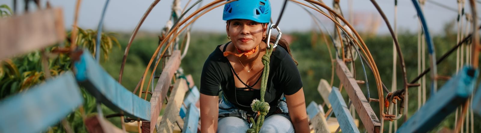 A girl inside a circular rope tunnel adventure structure at Daksh Resort & Amusement Park.