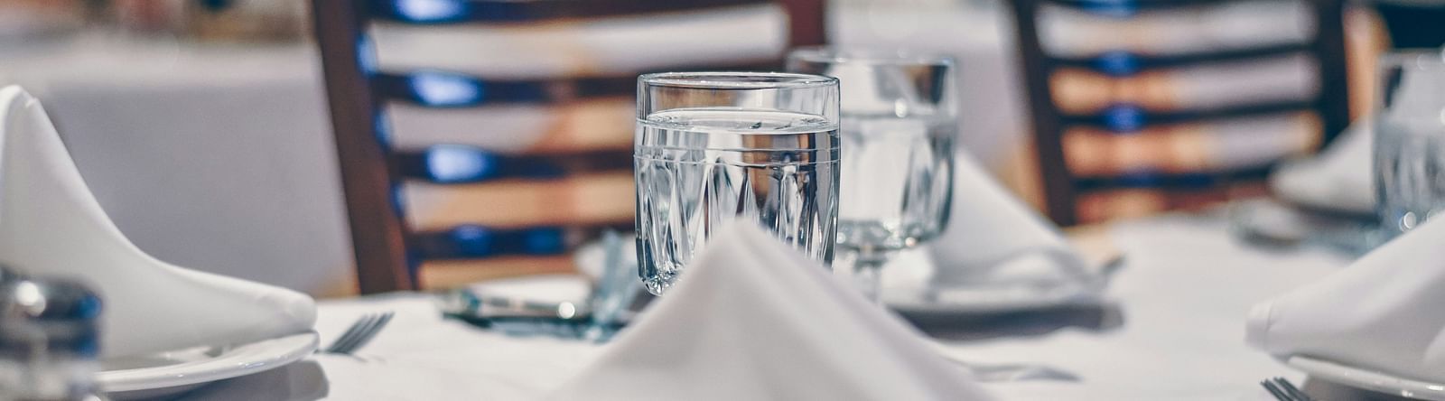 a plate with a napkin placed on it and a glass of water placed by its side