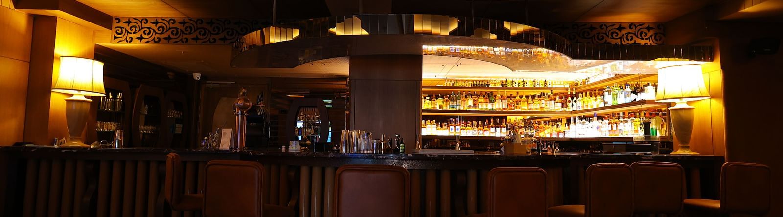 Image of bar area of JBs lounge with chairs, tables and stacked bar rack