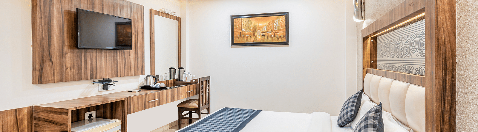 A cozy room at Hotel Moti Palace featuring a comfy bed, a flat-screen TV, and a dressing table.