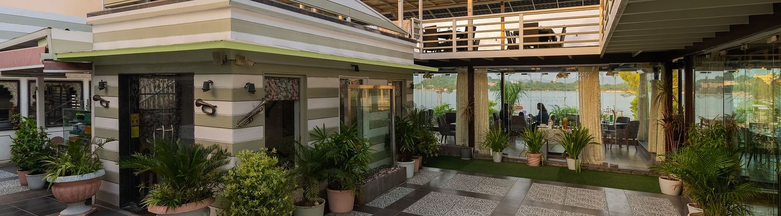 Rooftop restaurant entrance of Panna Vilas Palce features potted plants for decoration, with glass panels separating the dining area.