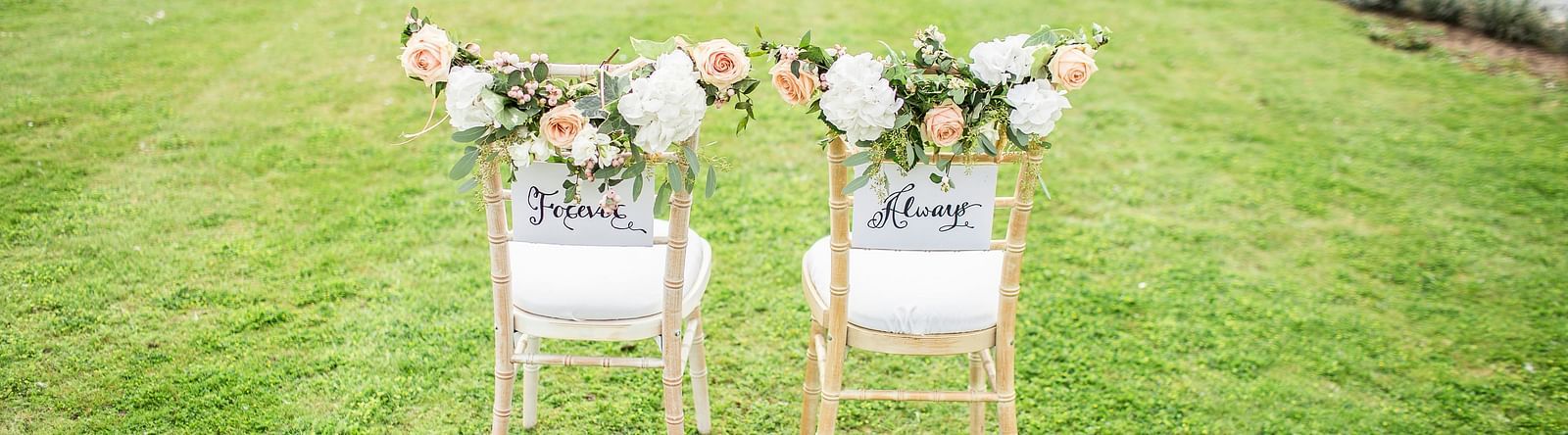 two chairs with a bouquet of flowers kept above it in a lawn area