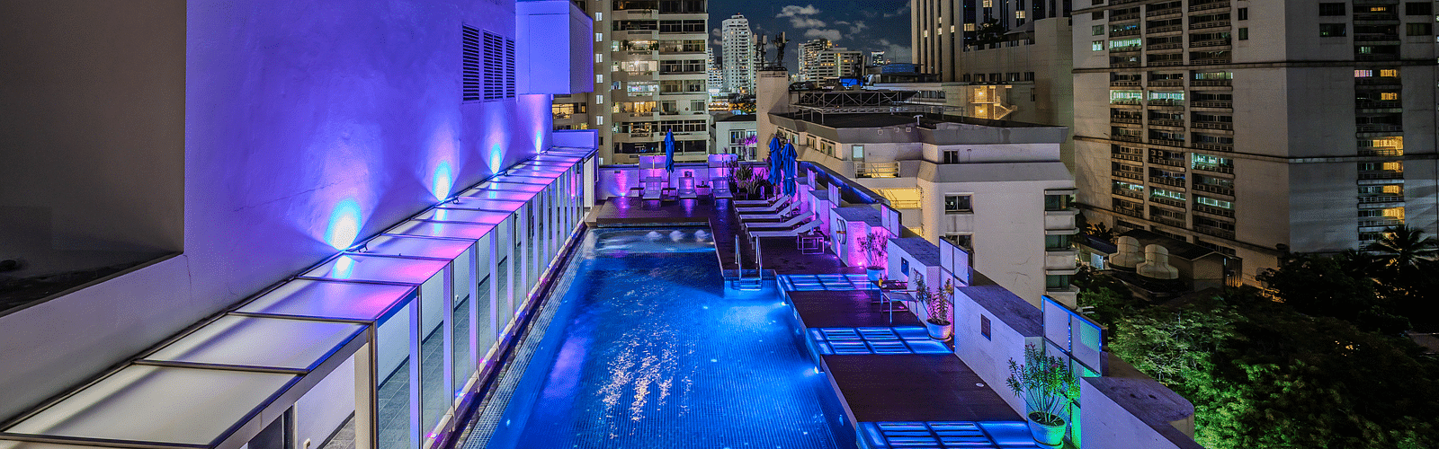 An overview of the rooftop swimming pool with the lights on  - Night Hotel Bangkok.
