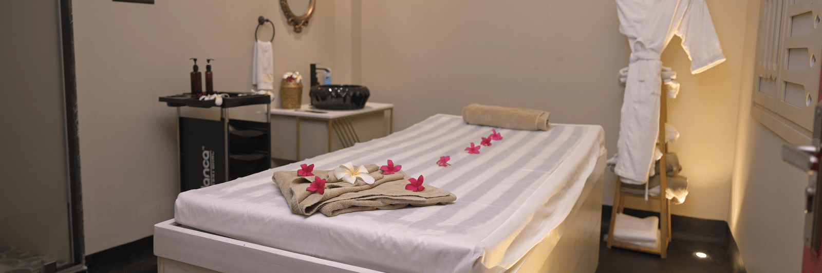 A spa room with a neatly arranged massage bed and treatment essentials at Hotel Sonar Bangla Mayapur.