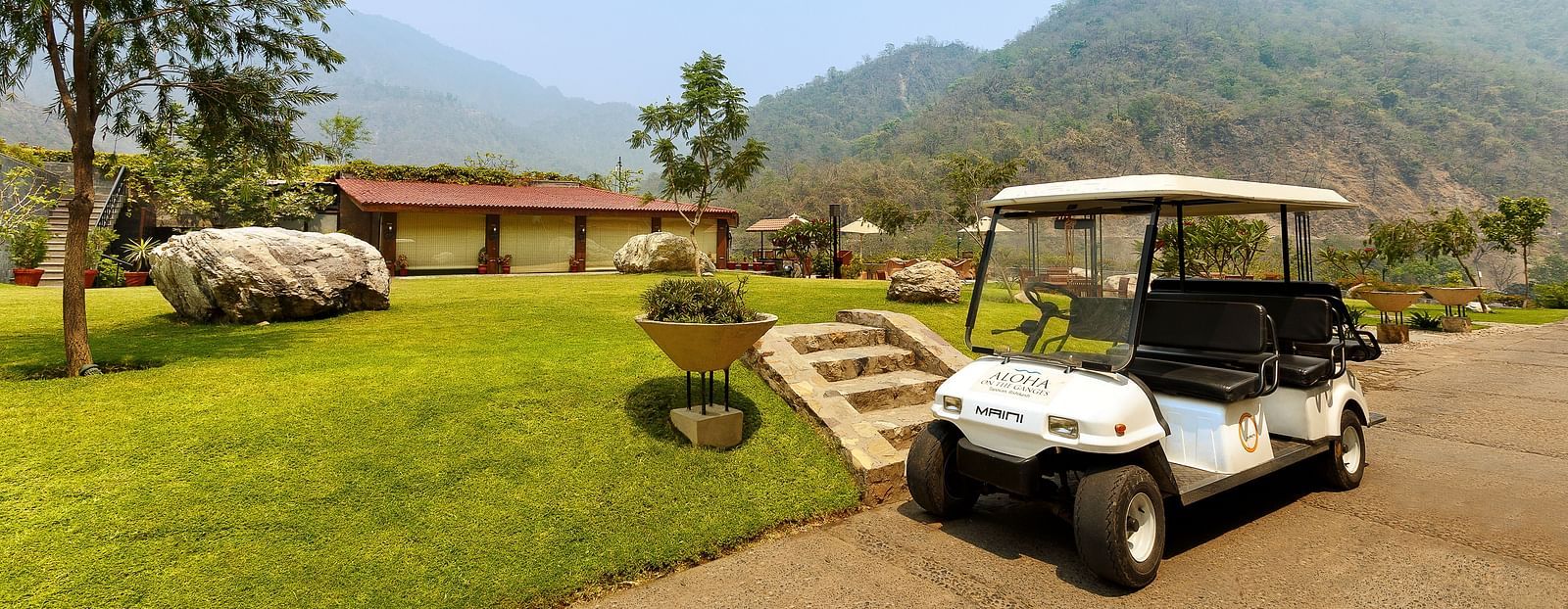 A small white pickup van parked in front of a garden.