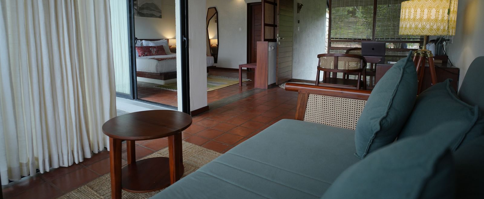 A spacious living area at Vaasta Vagamon with a sofa, a coffee table, and an open doorway leading to a bedroom.