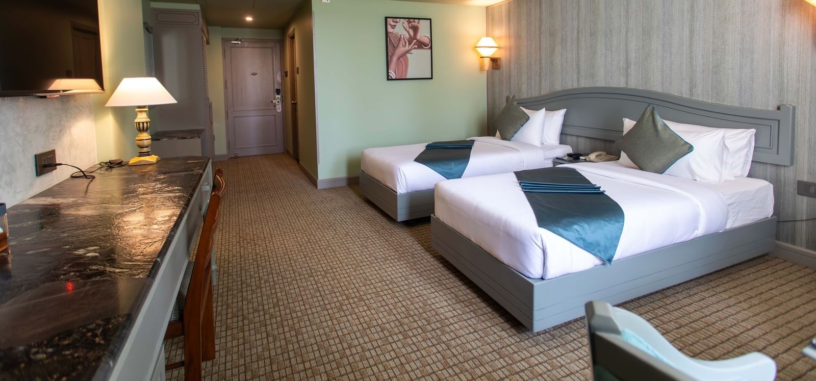 A well-appointed guest room at Shilton International, Kochi, with two beds and a desk area.