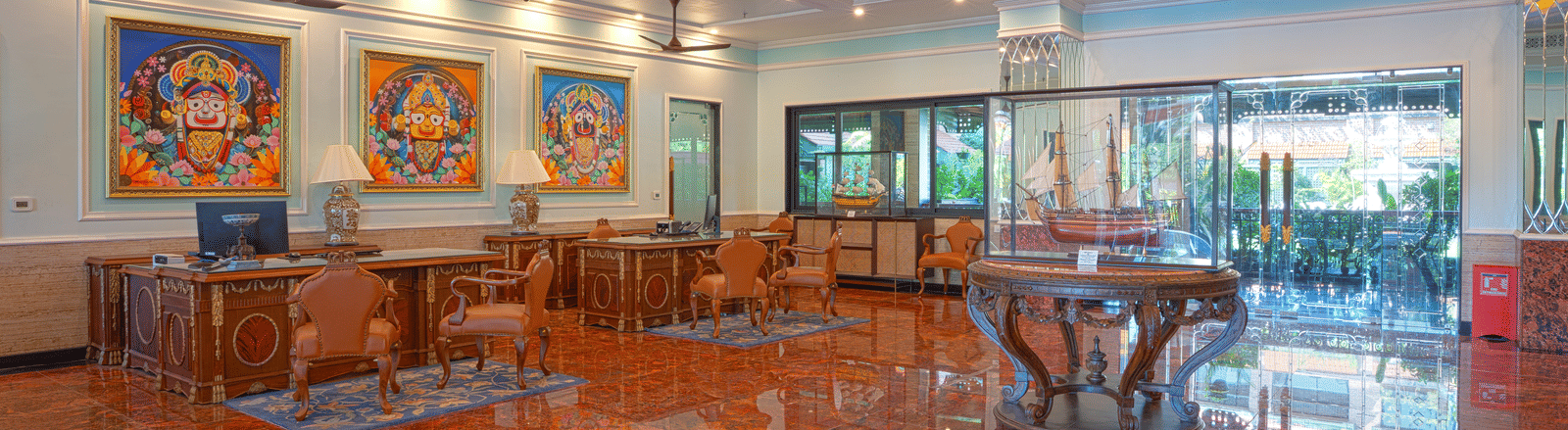A wide view of the lobby lounge with seating area, decorative artwork, and a polished reddish marble floor at MAYFAIR Bay Resort, Paradeep.