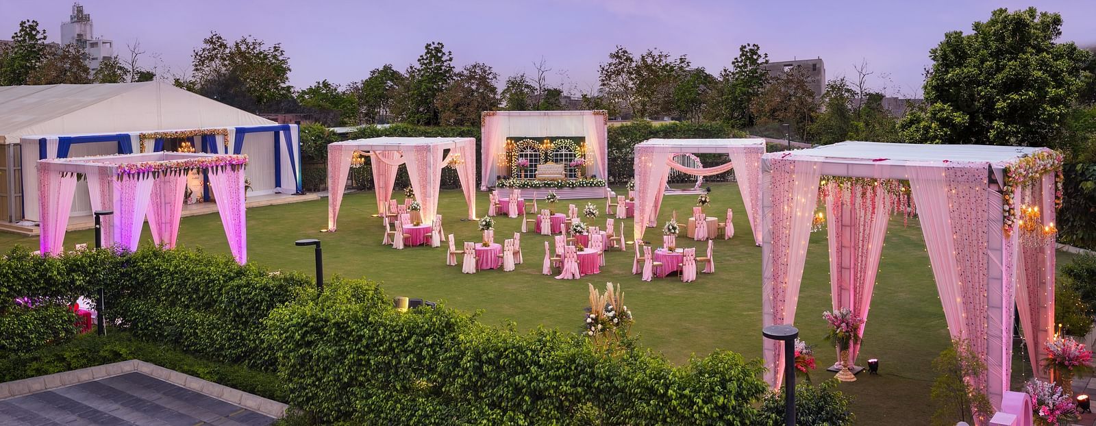 a view of a group of canopies in an open space with clusters of tables and chairs scattered across the space - The Hideaway Banquets & Lawns, Greater Noida