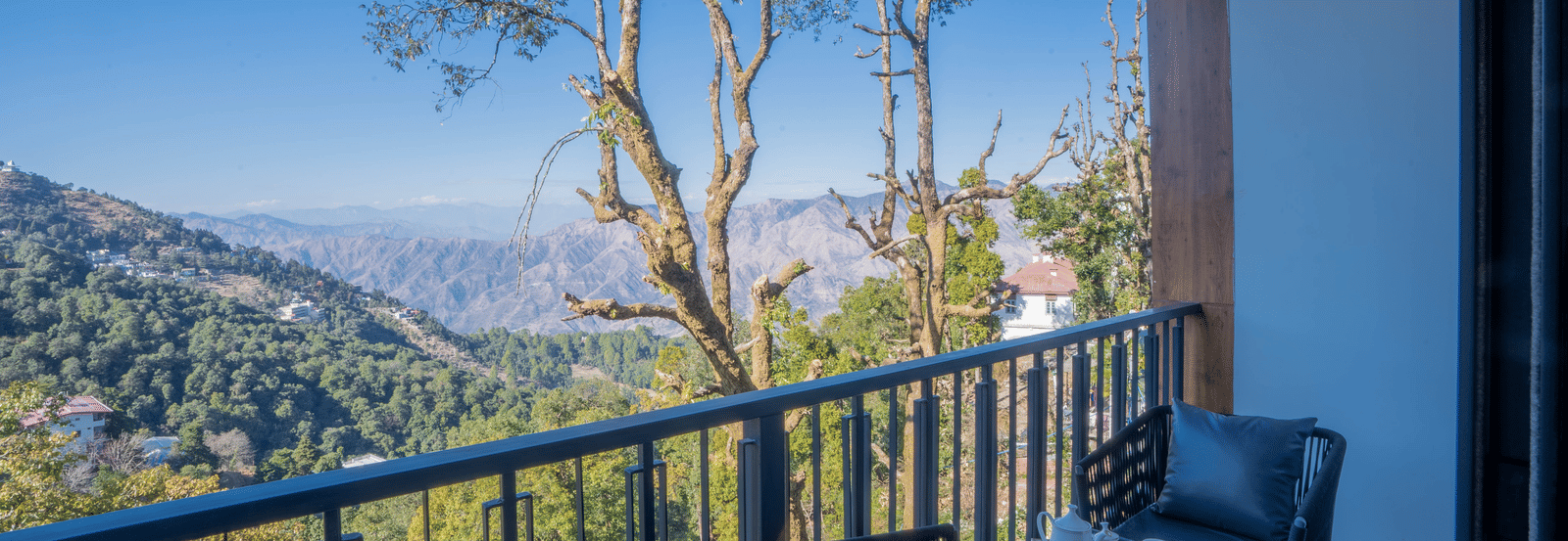 The private balcony at the Executive Room With Balcony & Valley View overlooking a lush green landscape on a bright day at Perfectstayz Premium Westend Mall Road, Mussoorie.
