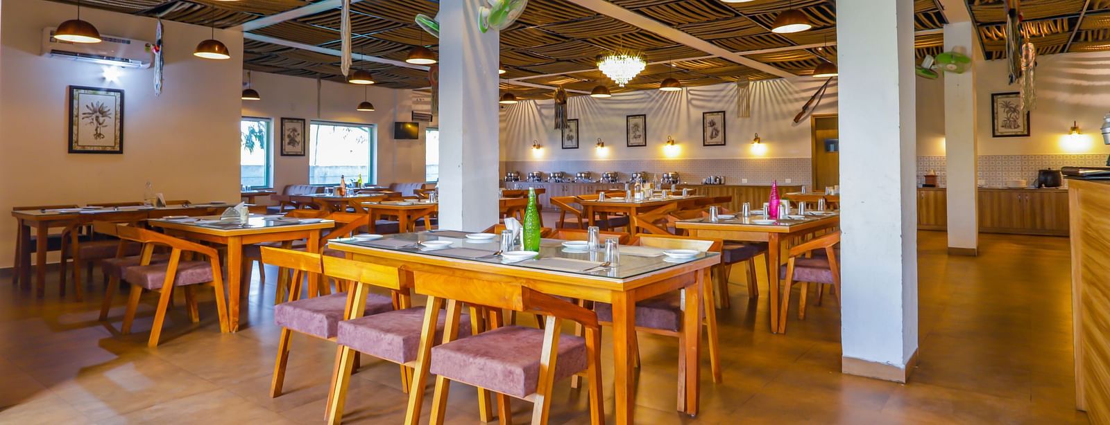 A bright dining hall at Vedikant Resorts The Mallard Corbett features wooden tables and colorful chairs.