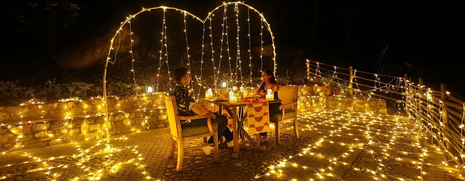 Two people enjoying a lavish dining setup in an open-air setting at The Sylvan Retreat, Dehradun.