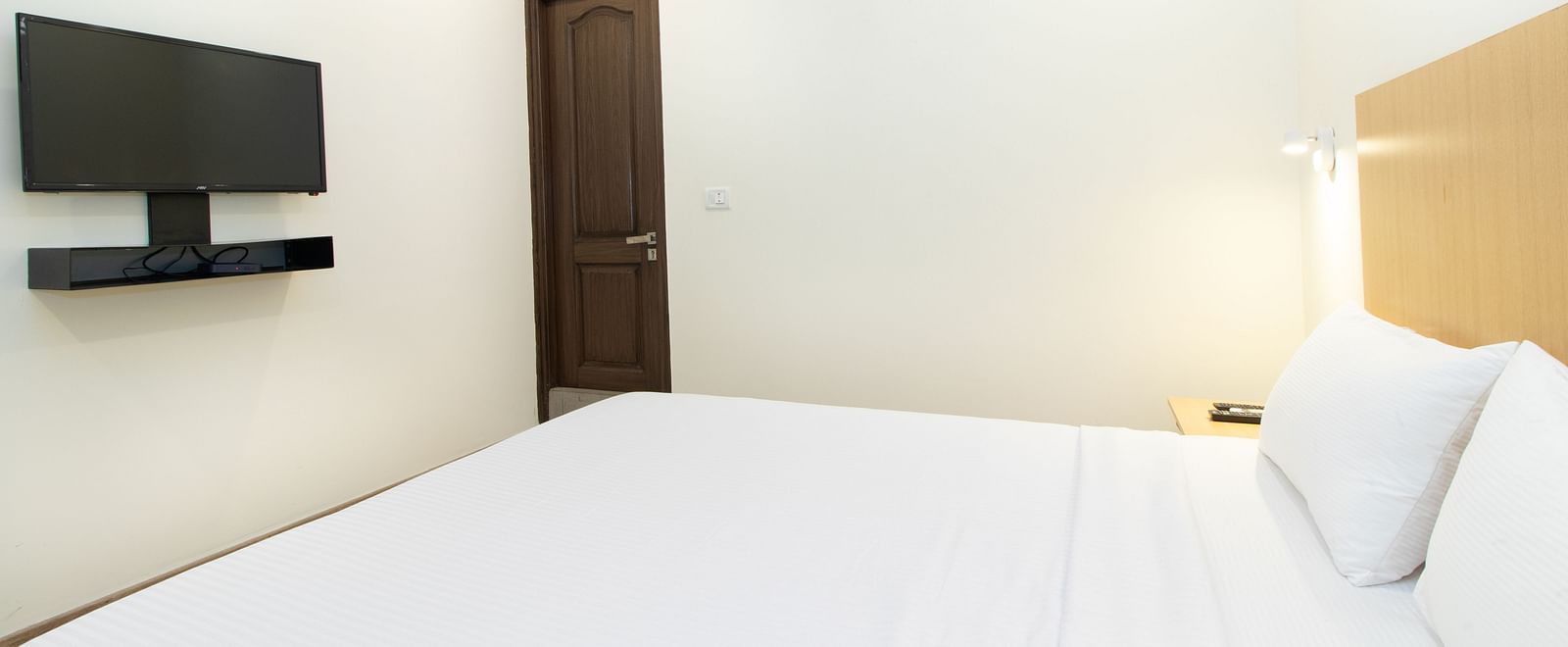 Bedroom featuring a double bed with white linens, and a wall-mounted television - Sanctum Suites Richmond Road, Bangalore