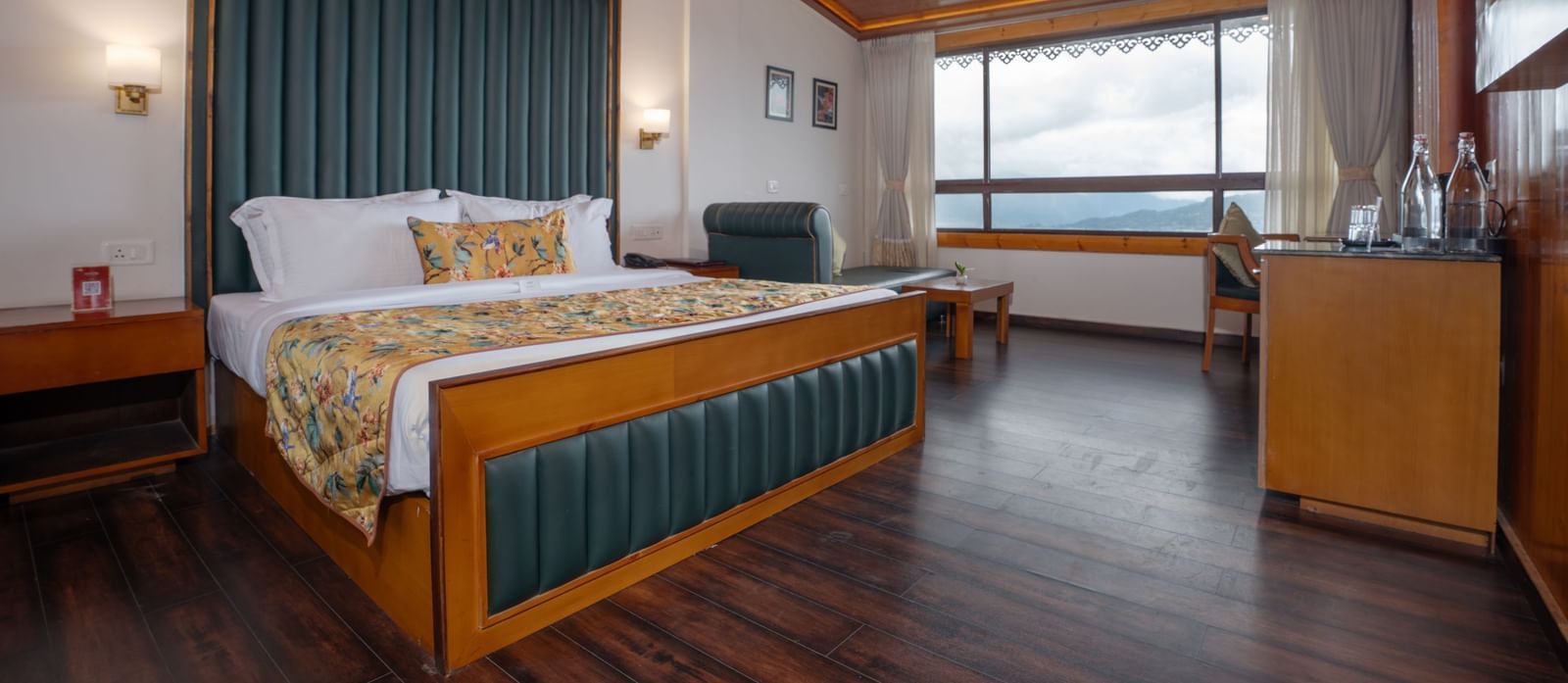 Premium Valley View Room at Summit North Star, Gangtok featuring a bed, a cabinet table, a seating area, and a large window with valley view.