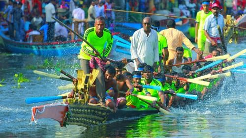 A group of people rowing a traditional long boat in a race on a lake, surrounded by other boats and spectators.