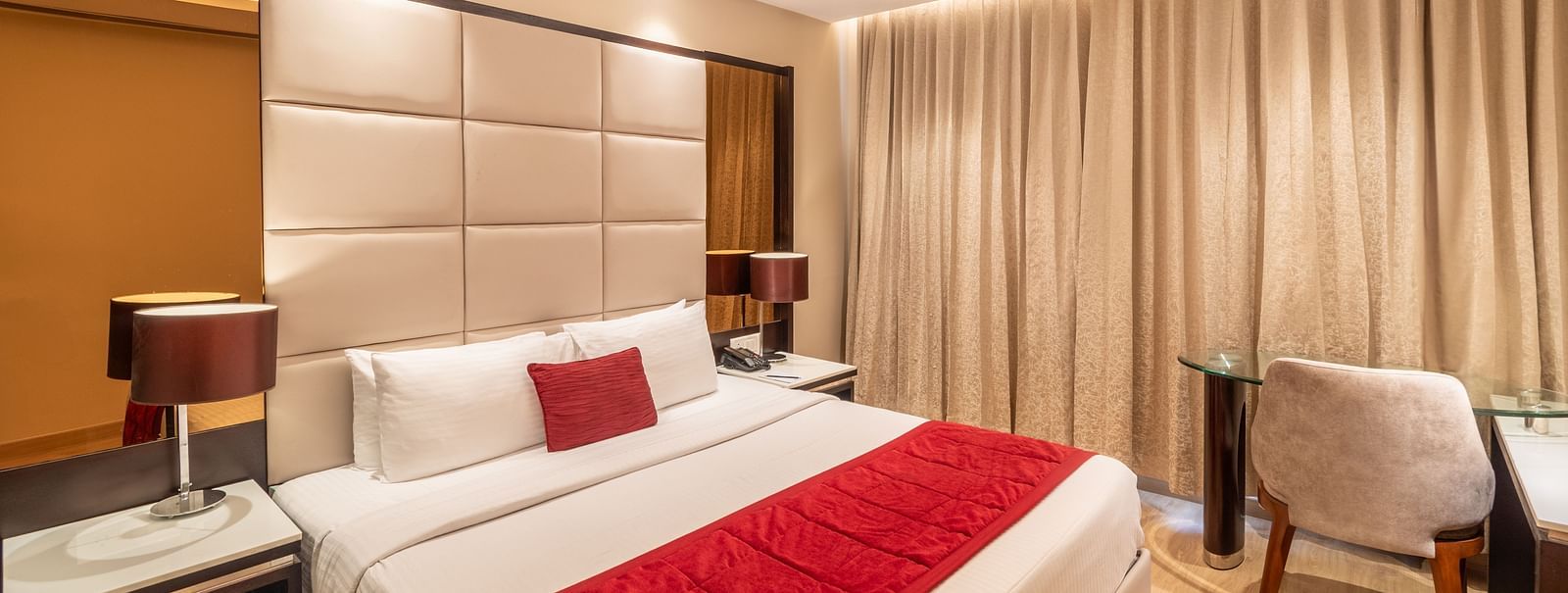 Fortuna suite's bedroom with full-length curtains, bedside table, and armchair- TGI Grand Fortuna, Krishnagiri Main Road, Hosur