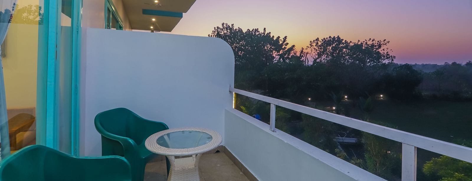 A balcony at Vedikant Resorts The Mallard Corbett features chairs and a table with a view of the landscape.