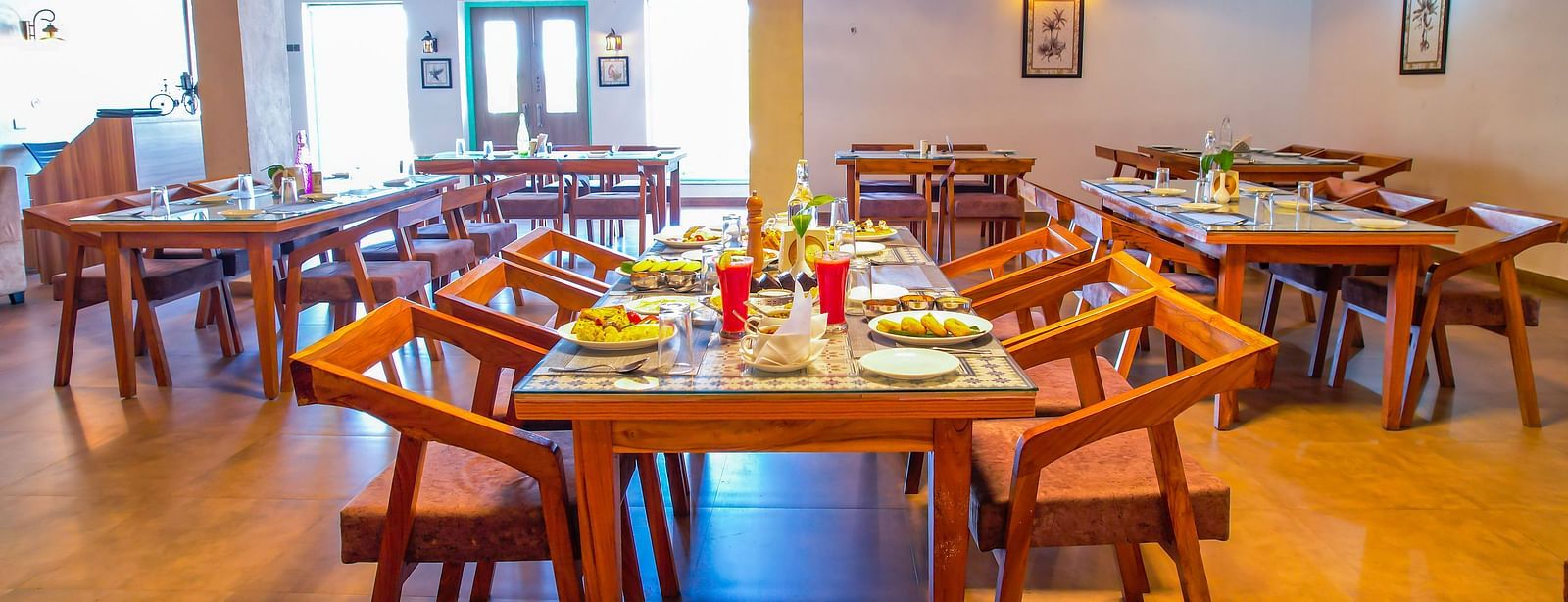 A dining area at Vedikant Resorts The Mallard Corbett displays wooden tables and chairs in a comfortable setting.