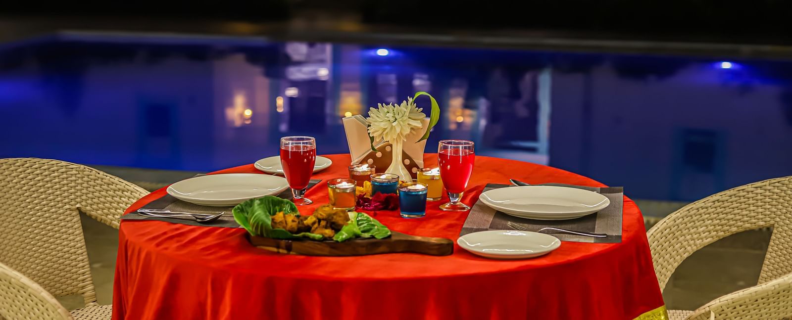 A poolside dining setup at Vedikant Resorts The Mallard Corbett at night features a decorated table and chairs.