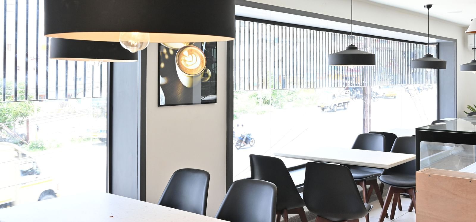 Side view of a coffee shop with chairs and lights hanging from the ceiling at Hotel Raai
