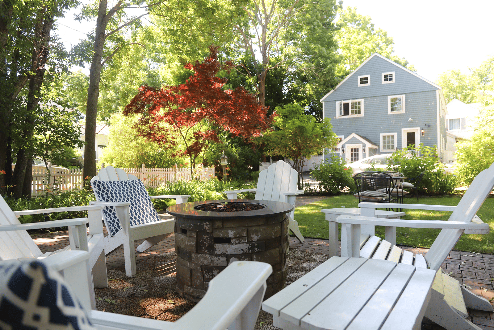 Outdoor garden seating area with white Adirondack chairs and a view of Hartstone Inn in the background.