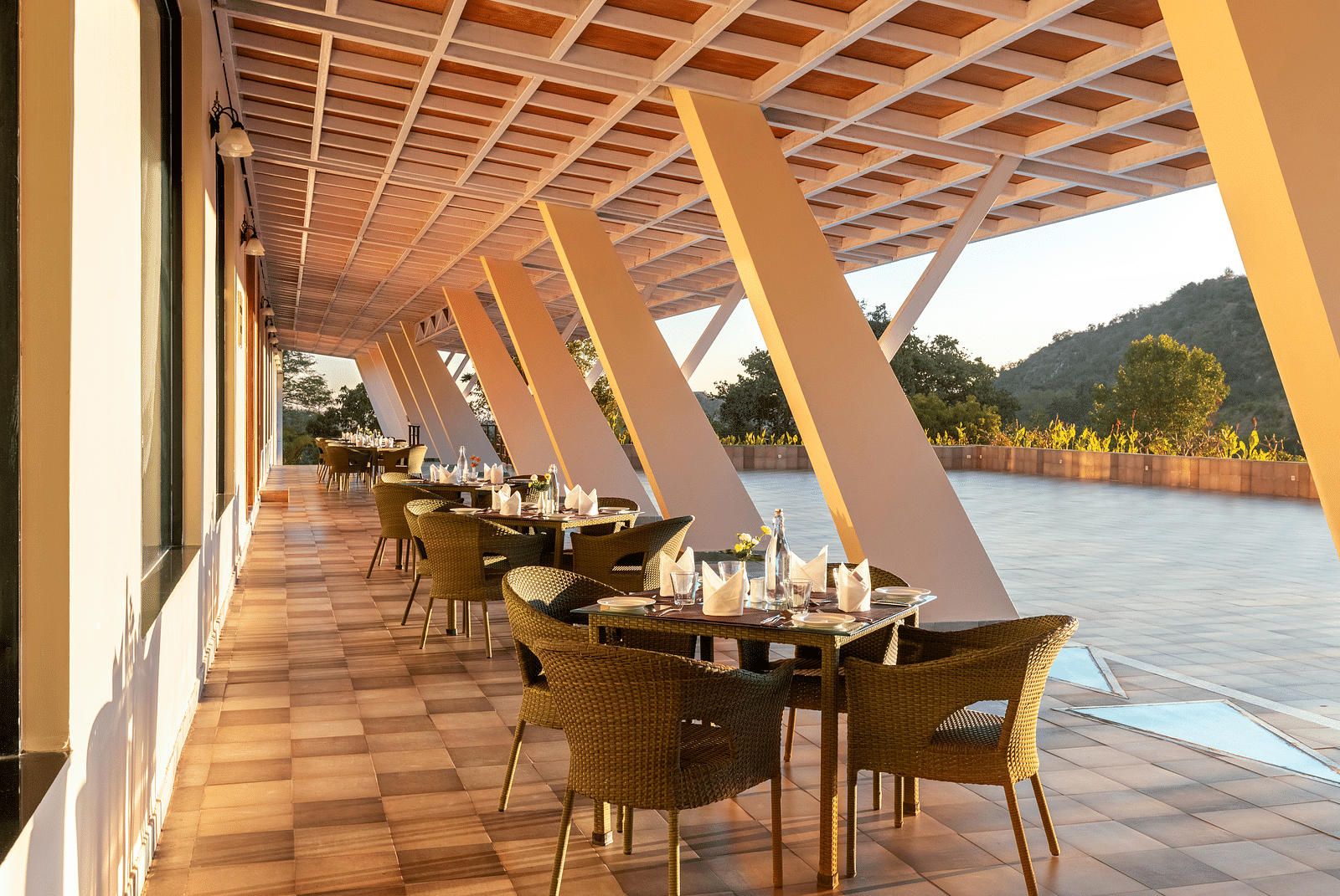 Outdoor dining area with sloped roof, tables, chairs, and a scenic view - Via Lakhela Resort & Spa