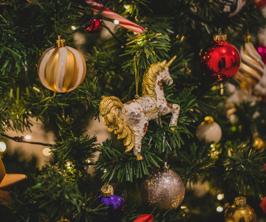 Christmas tree decorated with several items like horse, bells, stars, balls, fairy lights, etc.