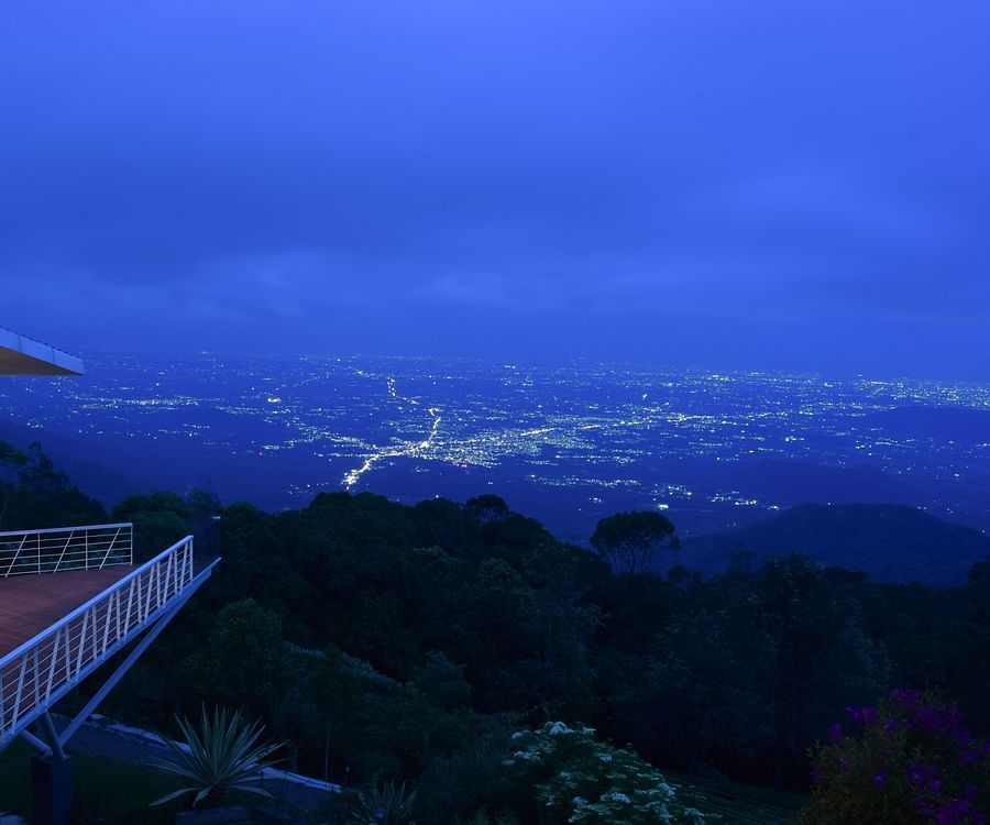 Twilight view of a balcony overlooking a lush valley and distant mountains at Ibex Resorts, Coonoor (Tapas).