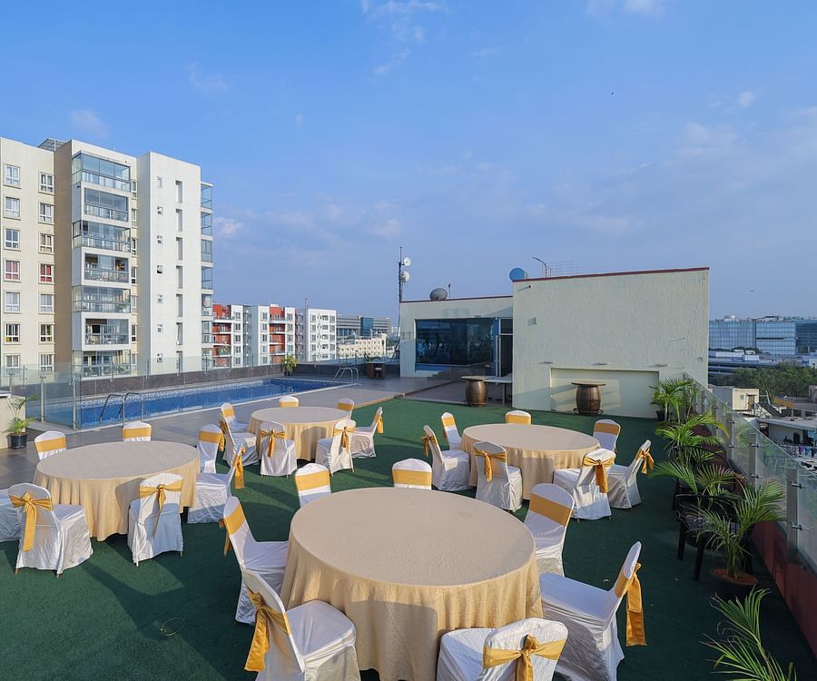 Terrace with round table seating arrangements and a swimming pool in the corner at Icon Premier Hotel by Bhagini, Devarabisanahalli