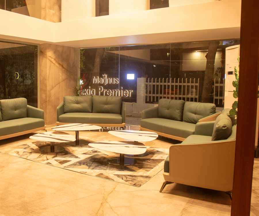 The lobby area with 4 sofas, 4 center table, marble sculpture, and glass entrance at Magnus Lxia Premier, Kalyani Nagar.
