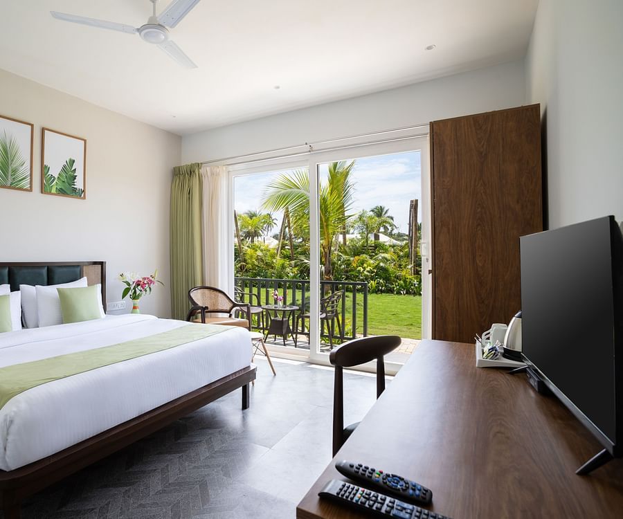 full view image of the premium cottage at sibaya beach resort in morjim beach, goa featuring a lush green scenic view from the huge windows in the room